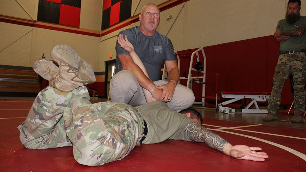 An instructor teaching safety in schools demonstrates an advanced cuffing position.