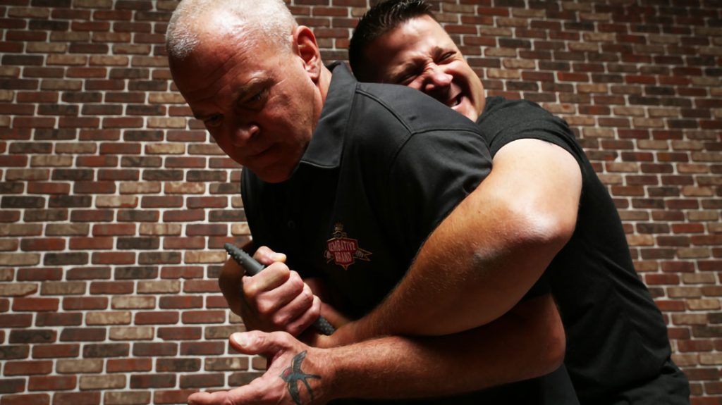 Kelly McCann digs a pocket stick into Rich Nance’s hand in a non-lethal self-defense technique.
